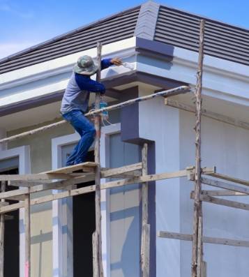 asian builder worker wooden scaffolding is painting roof structure modern house